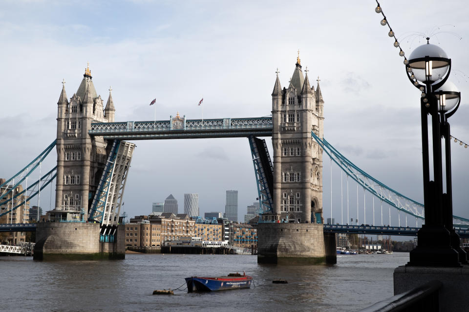 A general view of an open Tower Bridge with the skyline of Canary Wharf, London.