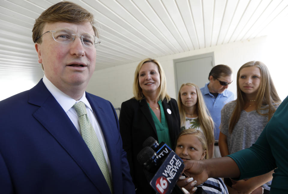 Republican Lt. Gov. Tate Reeves, a gubernatorial candidate, left, responds to a reporter's question after voting in the party primary at a Flowood, Miss., precinct, with his family, Tuesday, Aug. 6, 2019. (AP Photo/Rogelio V. Solis)