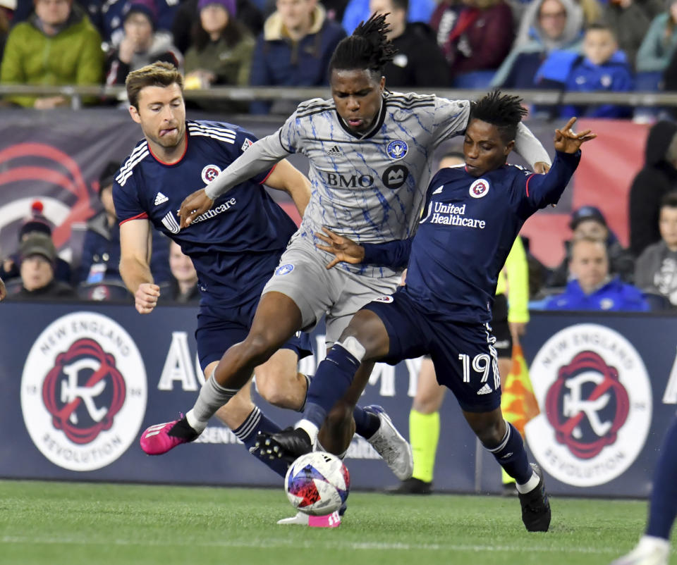 New England Revolution defender Dave Romney, left, and forward Latif Blessing (19) defend the ball from CF Montreal forward Chinonso Offor, center, in the first half of an MLS soccer match Saturday, April 8, 2023, in Foxborough, Mass. (AP Photo/Mark Stockwell)