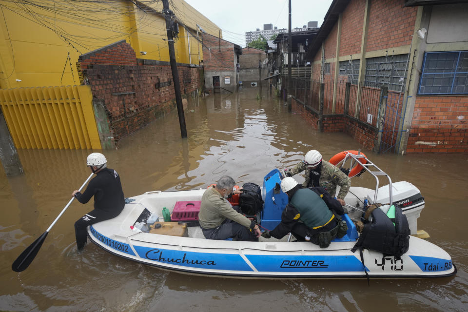 Volunteers evacuate a resident through a street flooded by heavy rains in Porto Alegre, Brazil, Sunday, May 12, 2024. (AP Photo/Andre Penner)