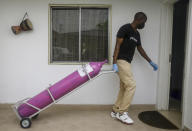 A worker from a private medical service brings oxygen bottles to aid the recovery of a COVID-19 patient, at her home in Lagos, Nigeria on Saturday, Feb. 6, 2021. A crisis over the supply of medical oxygen for coronavirus patients has struck in Africa and Latin America, where warnings went unheeded at the start of the pandemic and doctors say the shortage has led to unnecessary deaths. (AP Photo/Sunday Alamba)