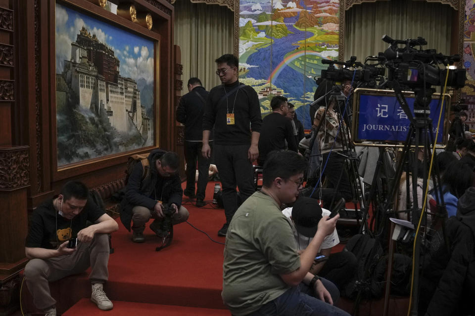 Journalists gather near a painting of Potala Palace during a deliberation on the government work report by Tibet delegations, on the sideline of the National People's Congress at the Great Hall of the People in Beijing, Wednesday, March 6, 2024. This year, China's national legislature resumed its annual in-person meetings in a way that it hadn't done since before the pandemic. Though officials say China is back to business, in practice, the meetings have become even more tightly scripted to broadcast Chinese leader Xi Jinping's message, leaving little room for the spontaneity and open engagement the sessions once offered before COVID-19.(AP Photo/Andy Wong, File)