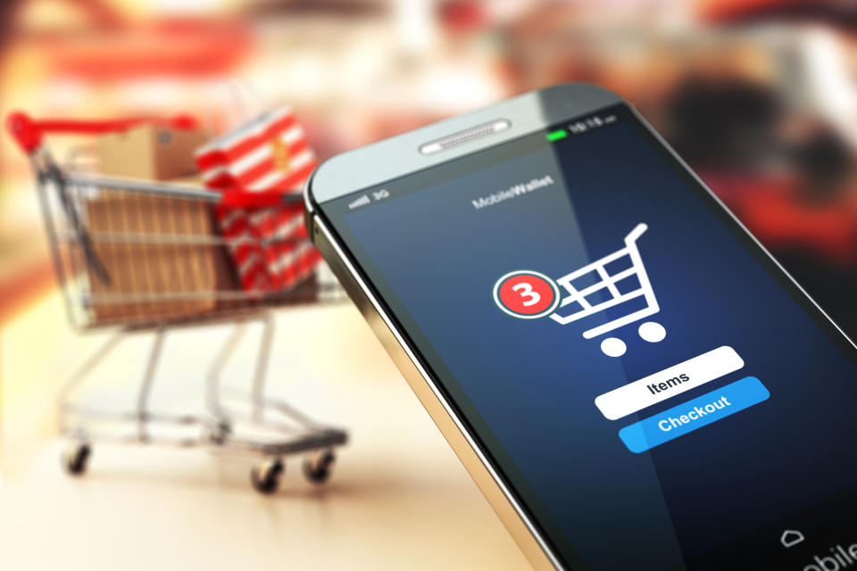 A smartphone displaying a mobile commerce app with a shopping cart in the background