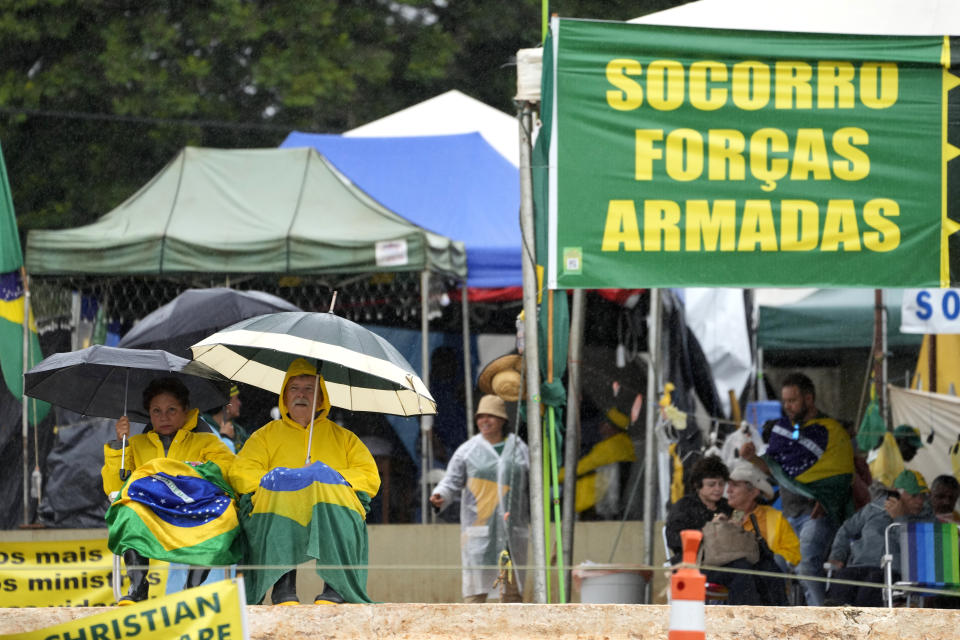 FILE - Supporters of outgoing President Jair Bolsonaro display banners with a message that reads in Portuguese; "Armed Forces Help" during a protest against the Oct. presidential election results, in front of the army headquarters in Brasilia, in Brasilia, Brazil, Monday, Dec. 26, 2022. Many of Bolsonaro’s far-right supporters have camped outside military buildings, pleading for army intervention that would keep Bolsonaro in power. (AP Photo/Eraldo Peres, File)