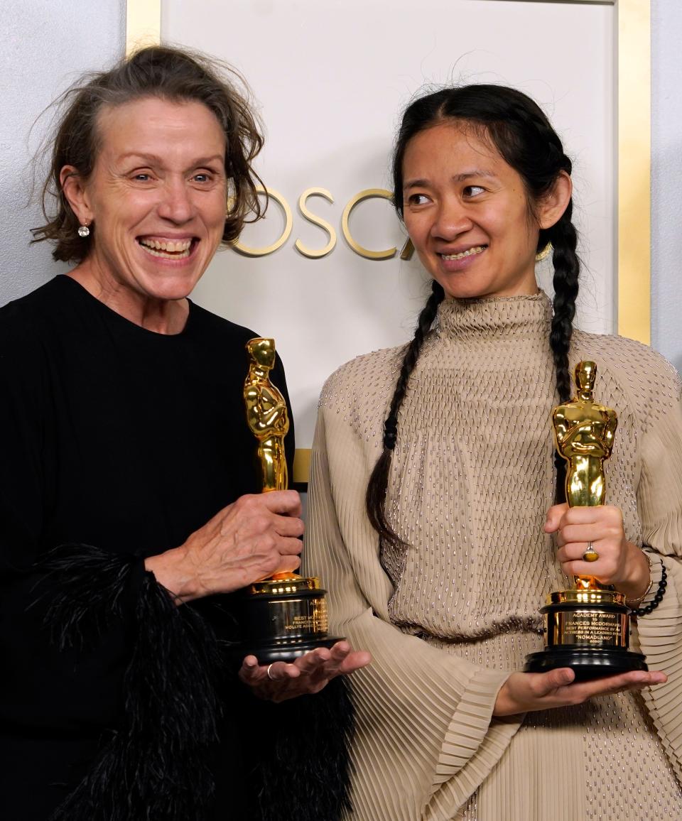 "Nomadland" actress/producer Frances McDormand, left, and writer/director/producer/editor Chloé Zhao hold their Oscars backstage Sunday night.