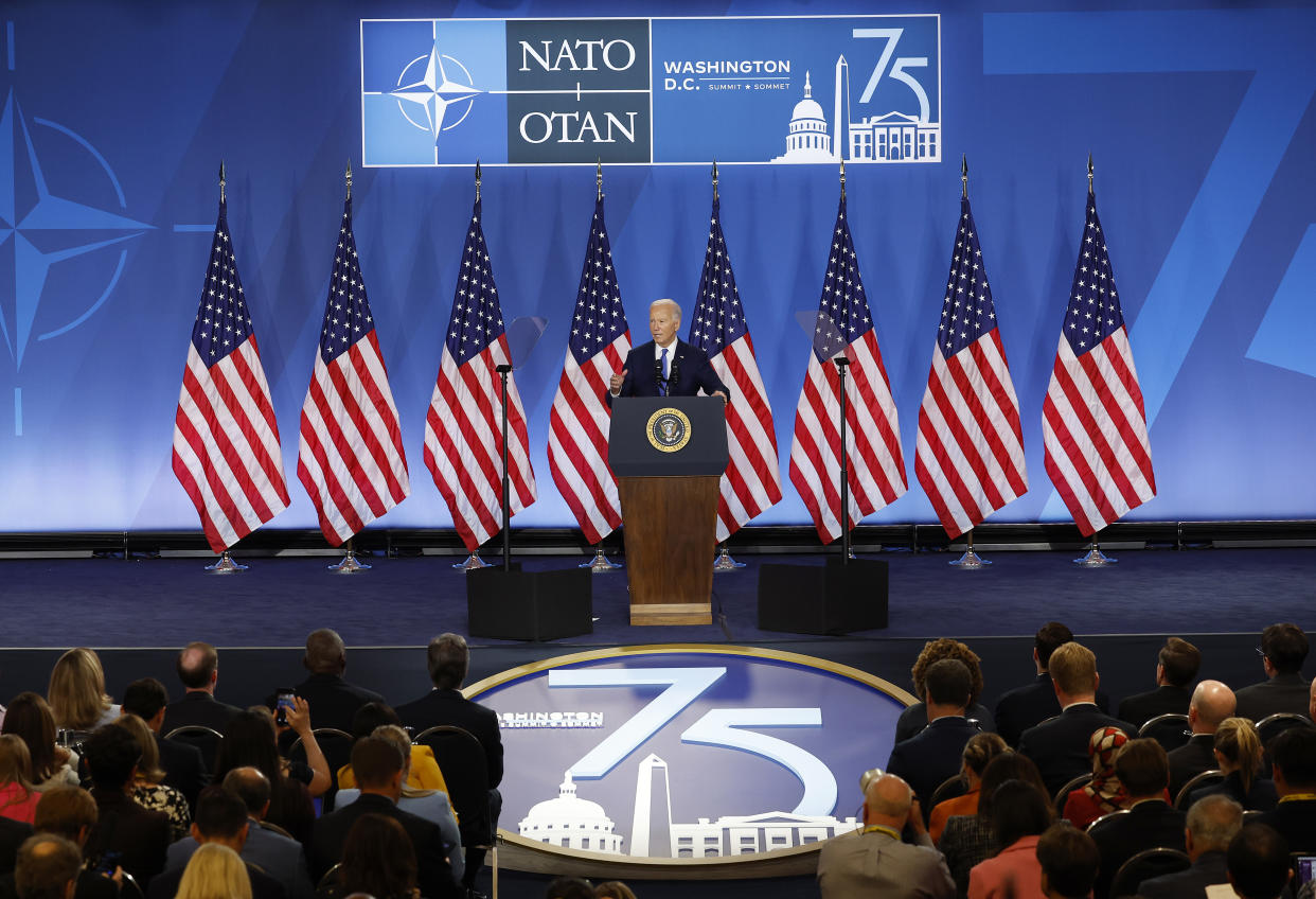 President Biden onstage at a podium in front of American flags.