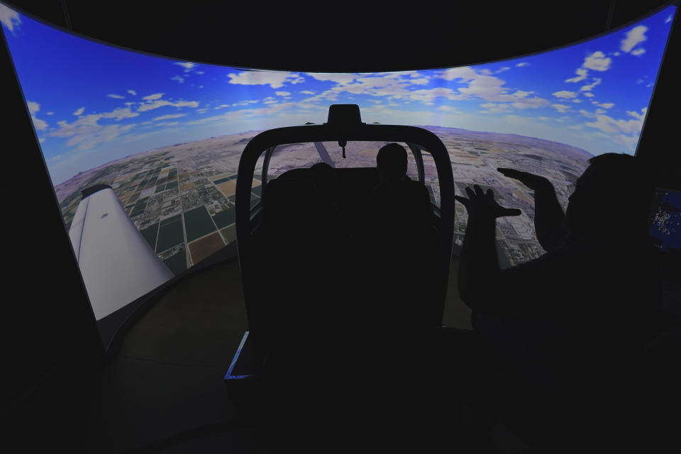 United Aviate Academy student pilot Lawrence Doruelo, left, is instructed in a flight simulator, Friday, Oct. 28, 2022, in Goodyear, Ariz. Pilot training programs are being created though airline executives warn that it could take years to produce enough pilots to meet Americans' growing desire to travel. (AP Photo/Matt York)