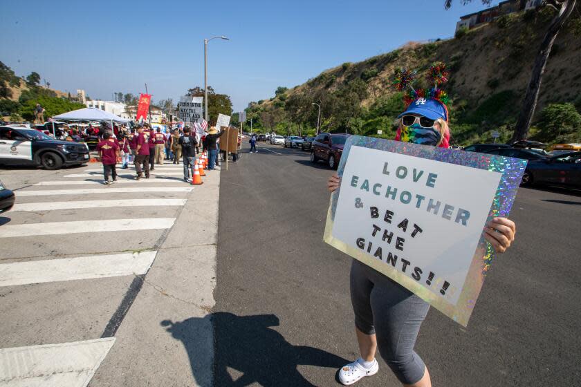 Jody Bender holds a sign for passing traffic near a gathering of Christian groups protesting near Dodger Stadium