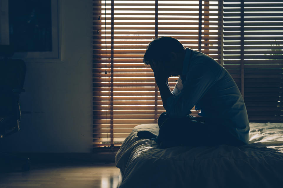 a person sitting in the dark with his hand to his face