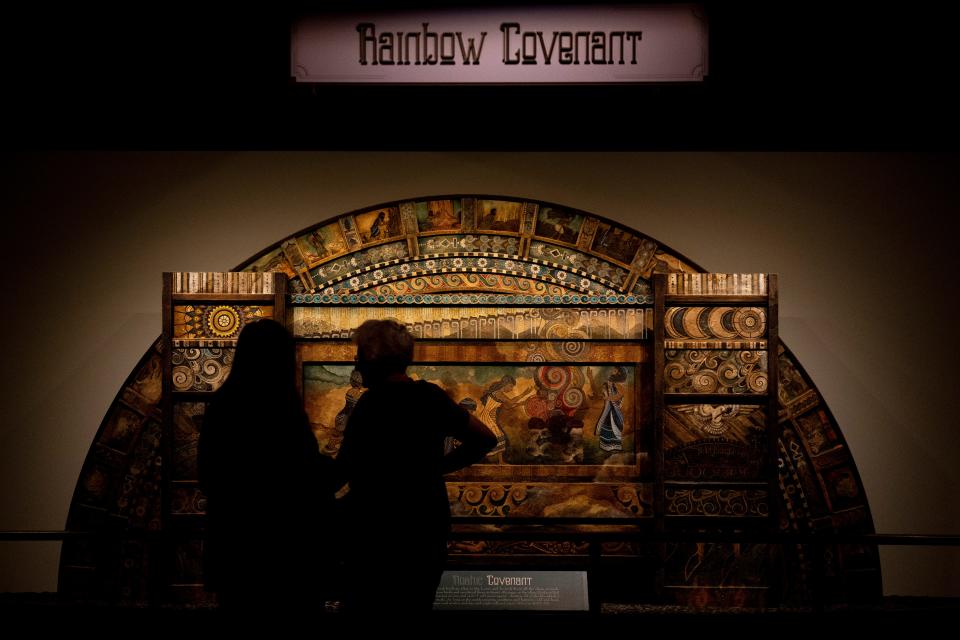 People stand next to a work of art depicting the covenant made between God and Noah in the Book of Genesis at Ark Encounters in Williamstown, Ky. The Ark Encounter features a 510-foot-long replica of Noah's Ark.