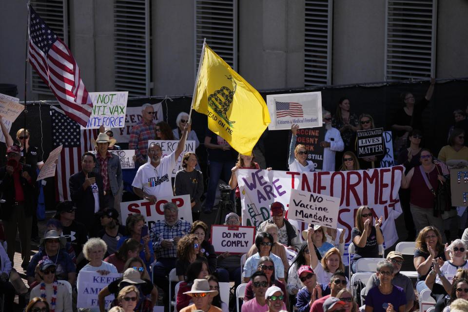 FILE - People carry signs and flags as several hundred anti-mandate demonstrators rally outside the Capitol during a special legislative session considering bills targeting COVID-19 vaccine mandates, Tuesday, Nov. 16, 2021, in Tallahassee, Fla. The vaccines’ first year has been rocky with the disappointment of breakthrough infections, the political strife over mandates and, now, worries about whether the mutant omicron will evade the vaccine's protection. (AP Photo/Rebecca Blackwell, File)