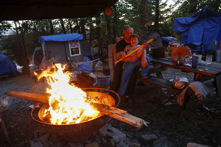 Matt Hannahs, 32, poses with his son Devin outside their tent by a wood fire at Nickelsville homeless tent encampment in Seattle, Washington October 13, 2015. REUTERS/Shannon Stapleton