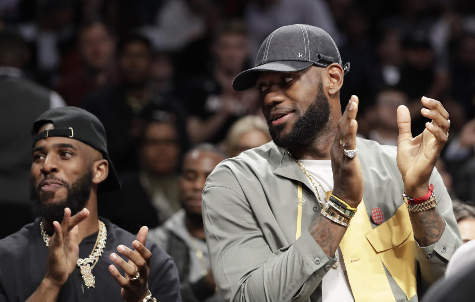 Chris Paul and LeBron James applaud during a ceremony at an NBA basketball game between the Brooklyn Nets and the Miami Heat, Wednesday, April 10, 2019, in New York. The pair were there to watch Heat guard Dwyane Wade play his last NBA game. (AP Photo/Kathy Willens)