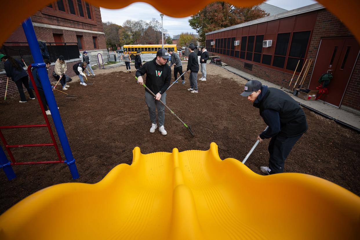 Aidan Busconi, center, and Christos Papvassiliou, both Holy Cross students, spread mulch on the new playground volunteers erected at Union Hill Elementary School Saturday.