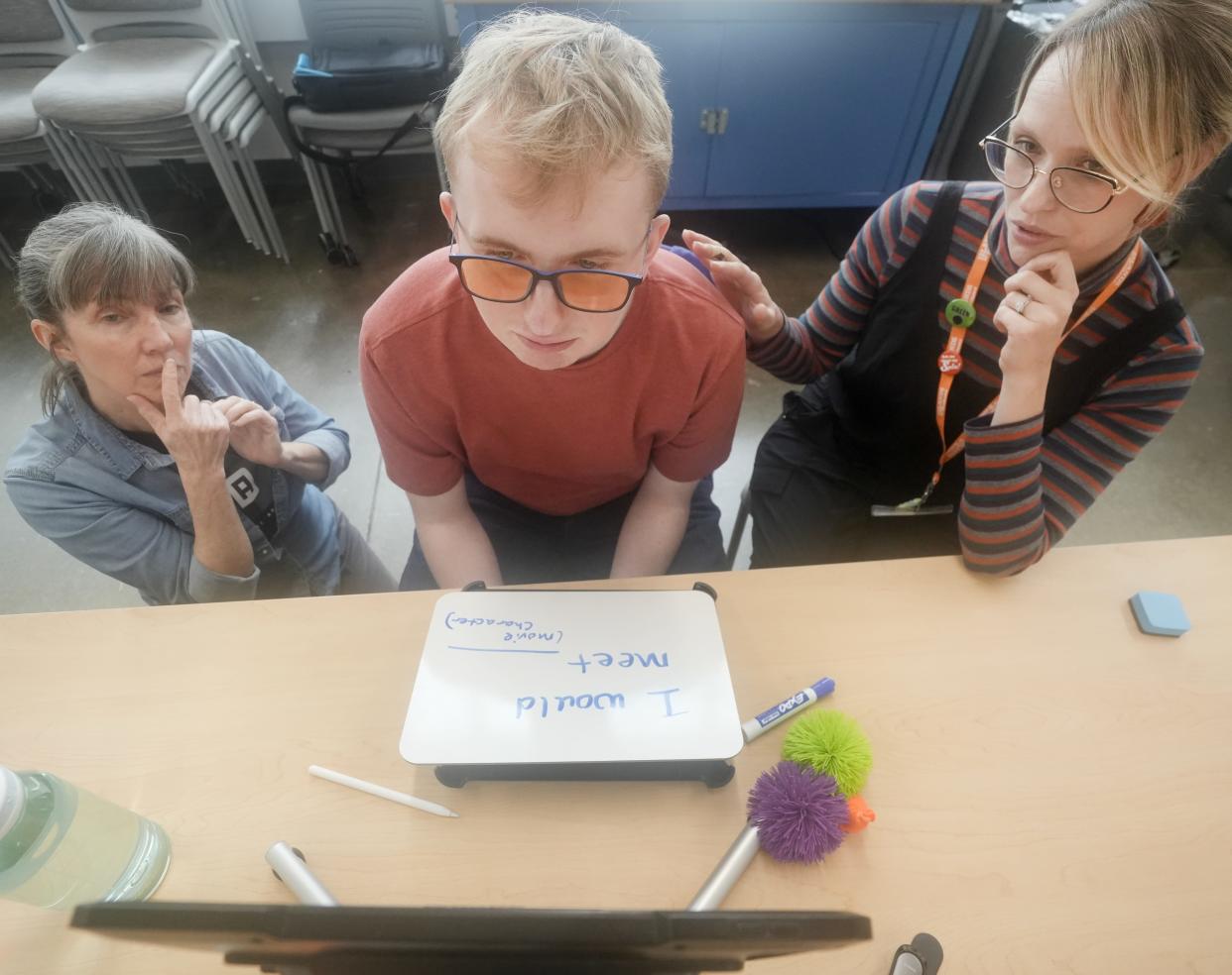 At an Islands of Brilliance workshop, Margaret Fairbanks (left) and Kate Siekman work with Grant, an autistic person who primarily uses assistive technology to speak.