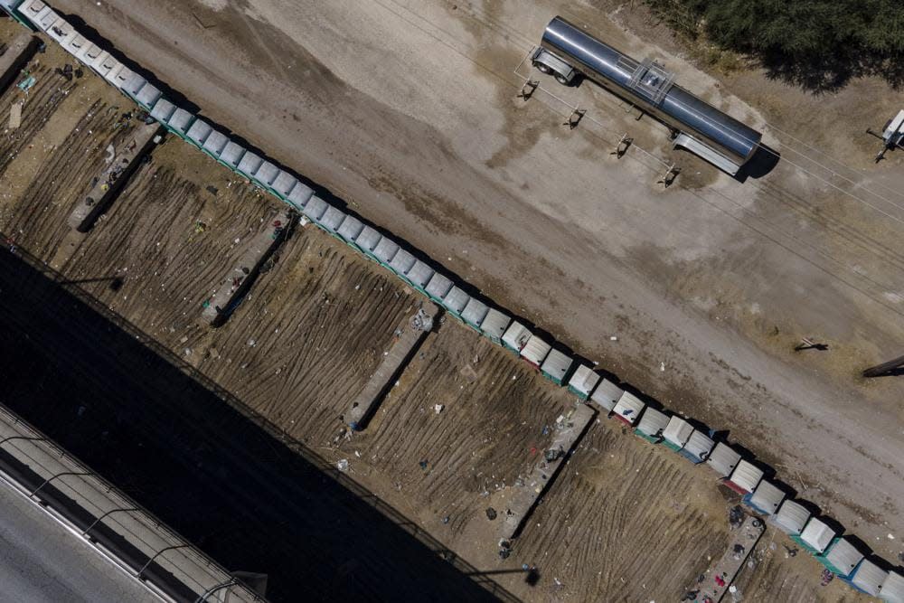 Portable restrooms are seen in an area used by migrants, many from Haiti, as an encampment along the Del Rio International Bridge, Friday, Sept. 24, 2021, in Del Rio, Texas. (AP Photo/Julio Cortez)