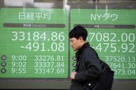 A person walks in front of an electronic stock board showing Japan's Nikkei 225 and New York Dow indexes at a securities firm Thursday, Dec. 21, 2023, in Tokyo. Asian shares fell Thursday after Wall Street hit the brakes on its big rally following disappointing corporate profit reports and warnings that the market had surged too far, too fast.(AP Photo/Eugene Hoshiko)