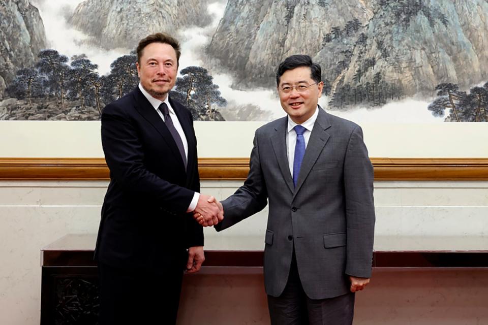 China's foreign minister Qin Gang, right, poses for photos with Tesla chief Elon Musk (AP)