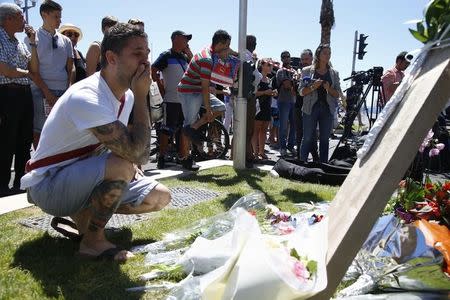 A man reacts in front of bouquets of flowers near the scene where a truck ran into a crowd at high speed killing scores and injuring more who were celebrating the Bastille Day national holiday, in Nice, France, July 15, 2016. REUTERS/Pascal Rossignol