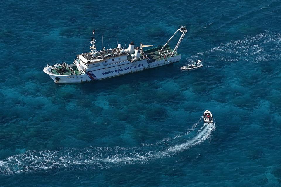 A China Coast Guard vessel and China Coast Guard personnel on a rubber boat.