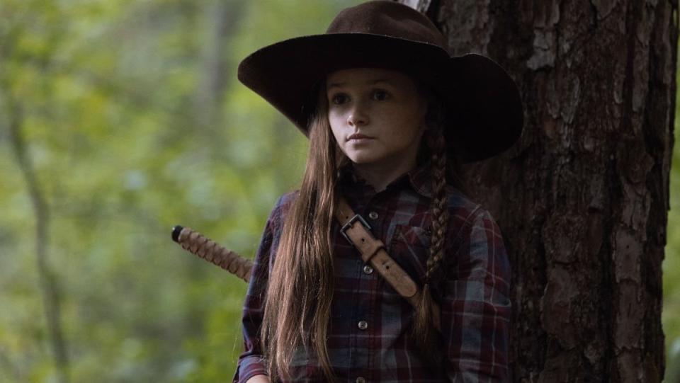 Judith Grimes wears Rick's Hat and stands against a tree