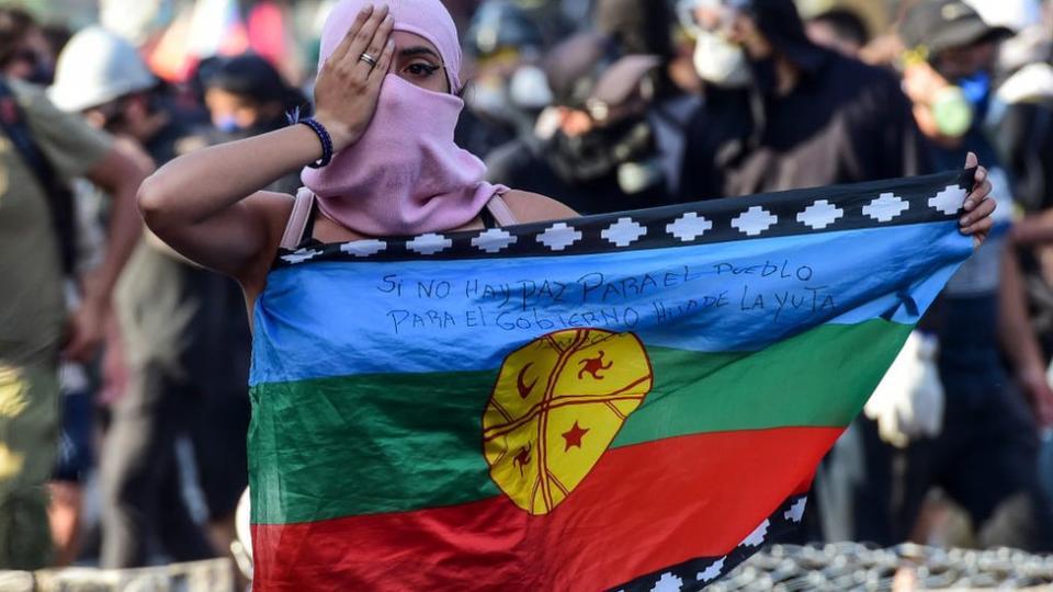 Mujer con bandera mapuche.