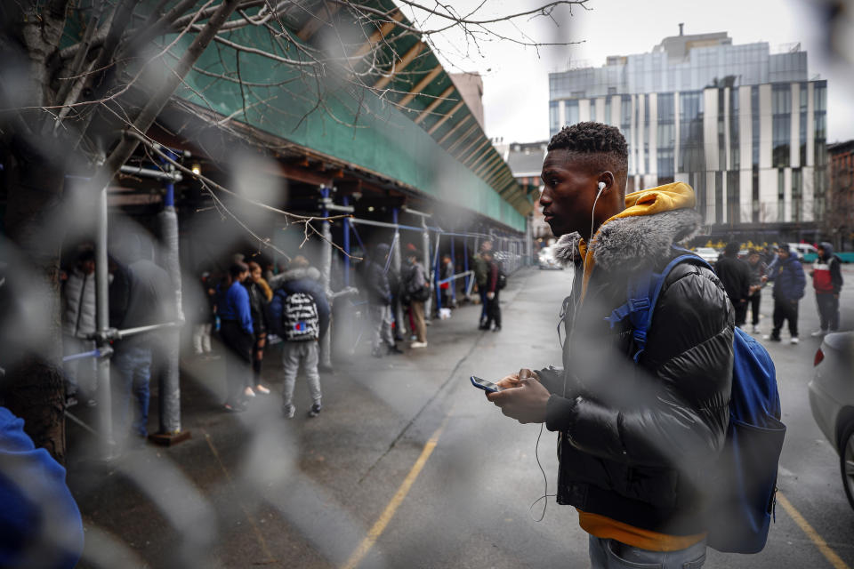 Student Laye Diakite lingers on premises after waiting to receive a school laptop for home study at the Lower East Side Preparatory School, Thursday, March 19, 2020, in New York, as coronavirus restrictions shuttered classrooms throughout the city. (AP Photo/John Minchillo)