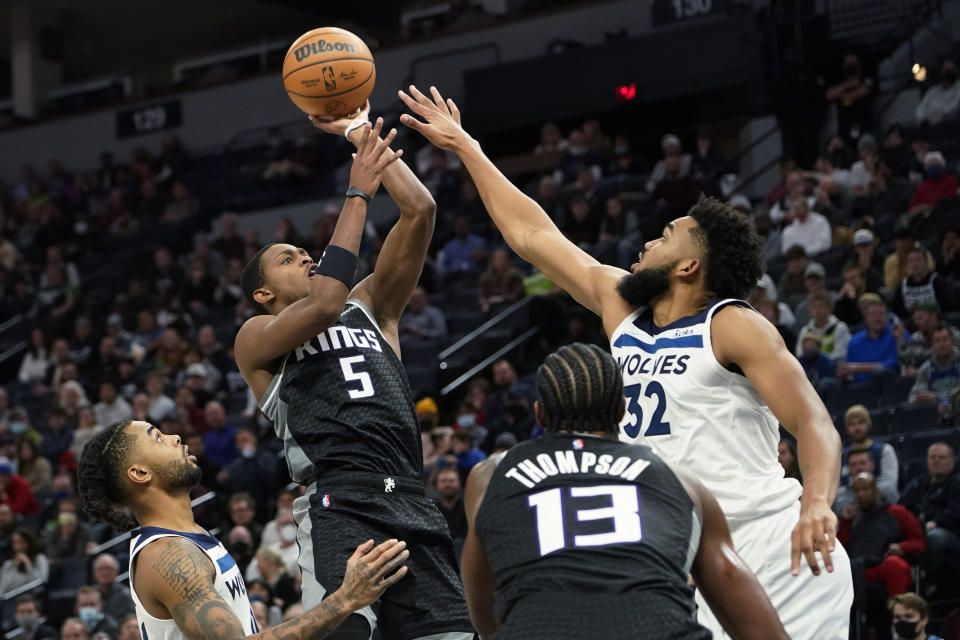 Sacramento Kings guard De'Aaron Fox (5) shoots over Minnesota Timberwolves center Karl-Anthony Towns as Kings center Tristan Thompson (13) and Timberwolves guard D'Angelo Russell, left, watch during the second half of an NBA basketball game Wednesday, Nov. 17, 2021, in Minneapolis. (AP Photo/Craig Lassig)