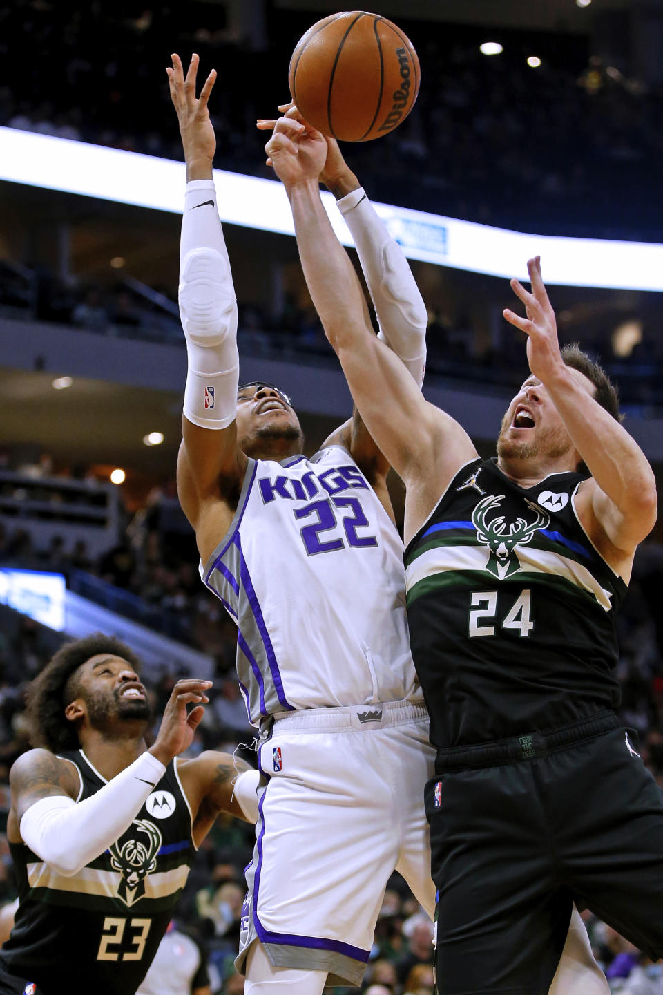 Sacramento Kings center Richaun Holmes (22) and Milwaukee Bucks guard Pat Connaughton (24) reach for the ball during the first half of an NBA basketball game Saturday, Jan. 22, 2022, in Milwaukee. (AP Photo/Jon Durr)