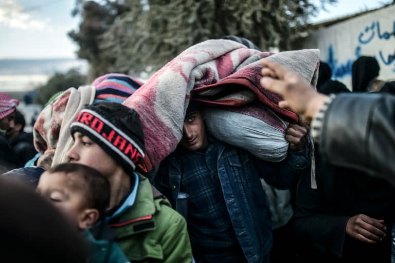 A man carrying belongings on his head looks on as Syrians fleeing the northern embattled city of Aleppo wait on February 5, 2016 in Bab-Al Salama, near Turkish crossing gate