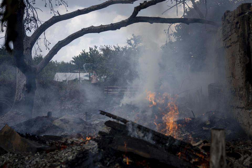 A local resident, back, tries to stop the fire at a neighbor's house destroyed by a Russian attack in Mykolaiv, Ukraine, Friday, Aug. 5, 2022. (AP Photo/Evgeniy Maloletka)