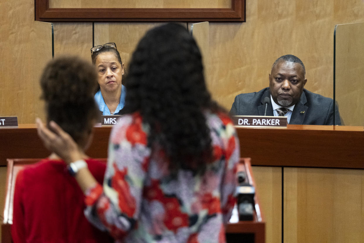 Djifa lee, a second-grade teacher at Saunders Elementary, center, stands with her daughter as she speaks in front of the Newport News School Board at the Newport News Public Schools Administration building on Tuesday, Jan. 17, 2023, in Newport News, Va. Community members spoke about issues and solutions to violence in schools following the shooting at Richneck Elementary by a six-year-old that left a teacher in critical condition. (Billy Schuerman/The Virginian-Pilot via AP)