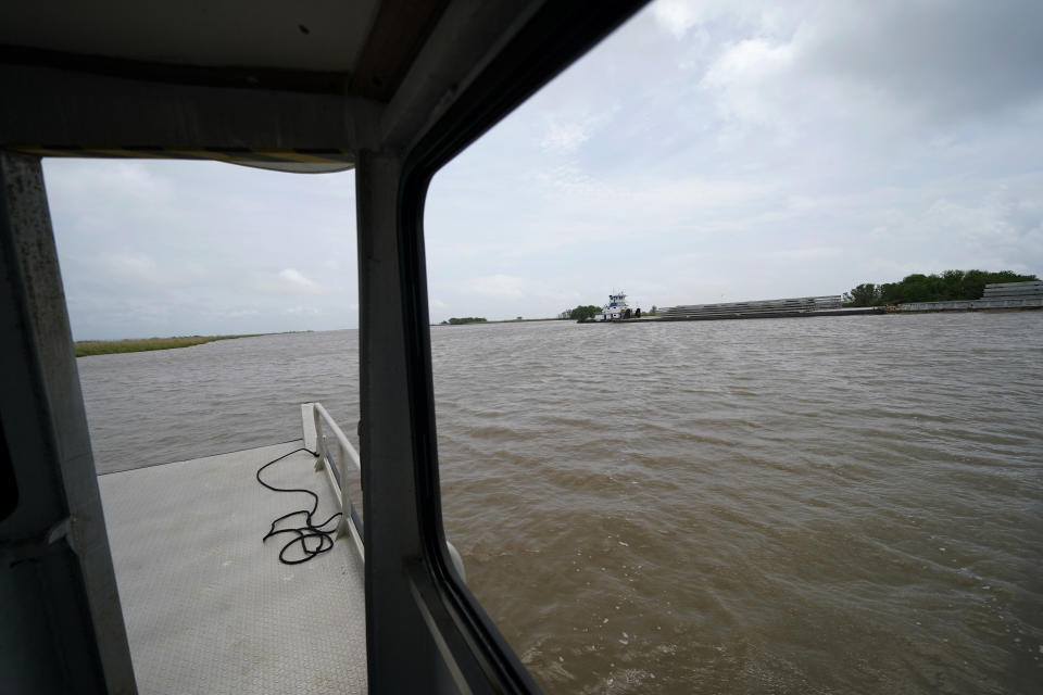 A tugboat pushes barges along the Intracoastal Waterway, which has encroached on marshland over the years, on Avery Island, La., where Tabasco brand pepper sauce is made, Tuesday, April 27, 2021. As storms grow more violent and Louisiana loses more of its coast, the family that makes Tabasco Sauce is fighting erosion in the marshland that buffers its factory from hurricanes and floods. Overall, it’s probably a standoff, says CEO and president Harold “Took” Osborn, great-great-grandson of the McIlhenny Co.’s founder. (AP Photo/Gerald Herbert)