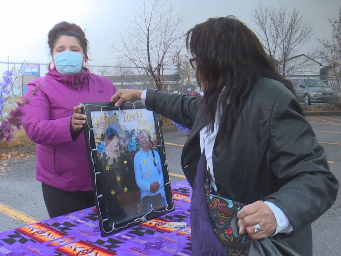 Sonny Crazy Bull's mother, Shelley, sets up a photo of her son at a memorial at the Marlborough CTrain station in Calgary on Oct. 23, 2021.  (Terri Trembath/CBC - image credit)