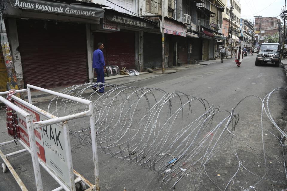 A pedestrian walks past a barbwire barricade set up by security officers in Jammu, India, Wednesday, Aug. 7, 2019. Indian lawmakers passed a bill Tuesday that strips statehood from the Indian-administered portion of Muslim-majority Kashmir, which remains under an indefinite security lockdown, actions that archrival Pakistan warned could lead to war. (AP Photo/Channi Anand)