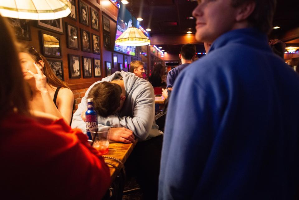 A dejected Kansas football fans puts his head down on a table inside Logie’s on Mass in Lawrence after the Jayhawks lost to Arkansas 55-53 in the Liberty Bowl.