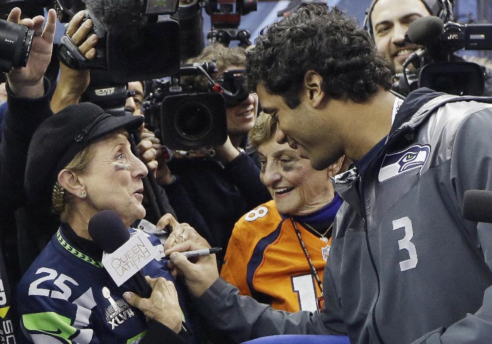 Seattle Seahawks' Russell Wilson signs autographs during media day for the NFL Super Bowl XLVIII football game Tuesday, Jan. 28, 2014, in Newark, N.J. (AP Photo/Mark Humphrey)