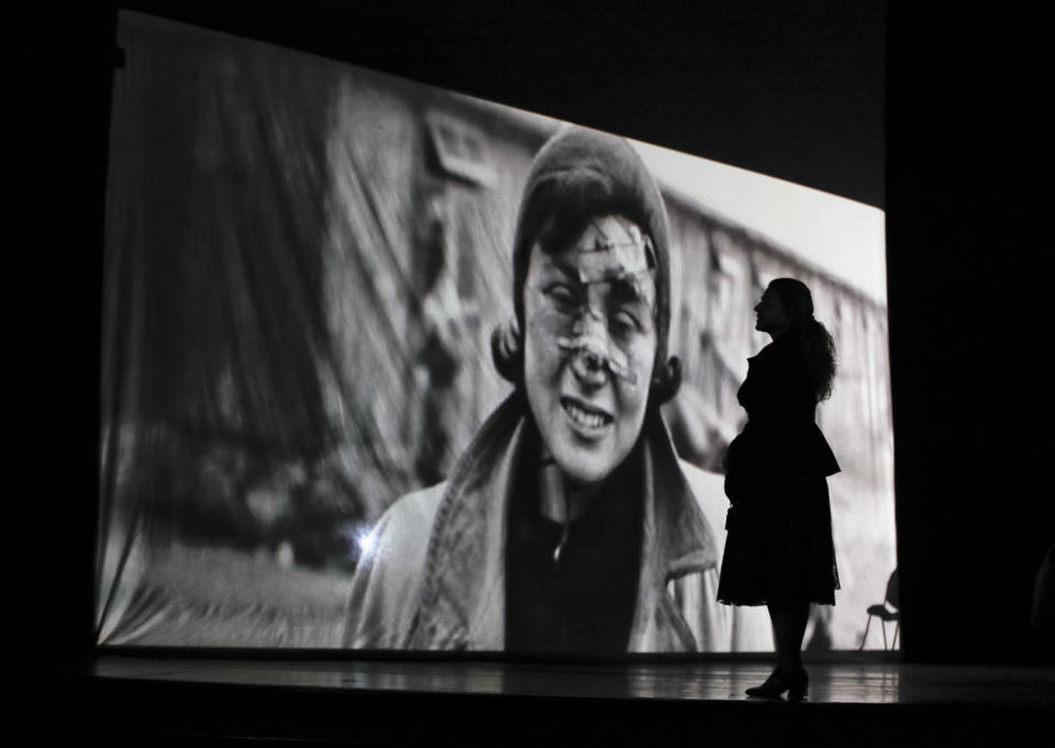 Silhouetted against an image of a death camp prisoner, an actress of the Romania's Jewish State Theatre rehearses the musical drama "The Lights of the Ghetto" a mix of music and stories by Holocaust survivors in Bucharest, Romania, Saturday, Jan. 26, 2019, a day before the premiere on International Holocaust Remembrance Day. About 280,000 Romanian Jews and 11,000 Romanian Roma, or Gypsies, were deported and killed during WWII when Romania was ruled by a pro-nazi regime. (AP Photo/Vadim Ghirda)