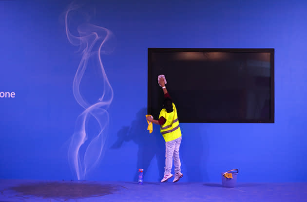 A worker jumps as she cleans a big screen at the start of the world's largest mobile phone trade show.