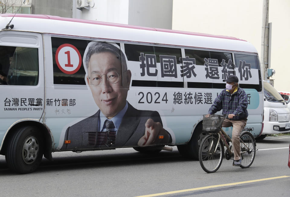 FILE - A man rides past a bus with a poster of Taiwan People's Party (TPP) presidential candidate Ko Wen-je running for the Taiwanese presidential election in Xiangshan District, southwest Hsinchu City, Taiwan, Thursday, Jan. 4, 2024. Taiwan will hold its presidential election on Jan. 13, 2024. (AP Photo/Chiang Ying-ying, File)