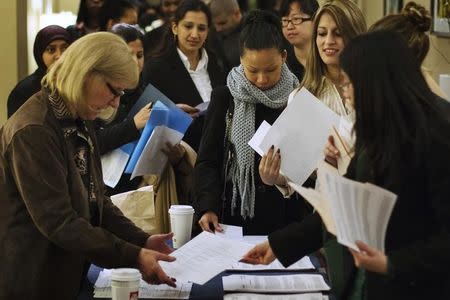 Job seekers adjust their paperwork as they wait in line to attend a job fair in New York February 28, 2013. REUTERS/Lucas Jackson