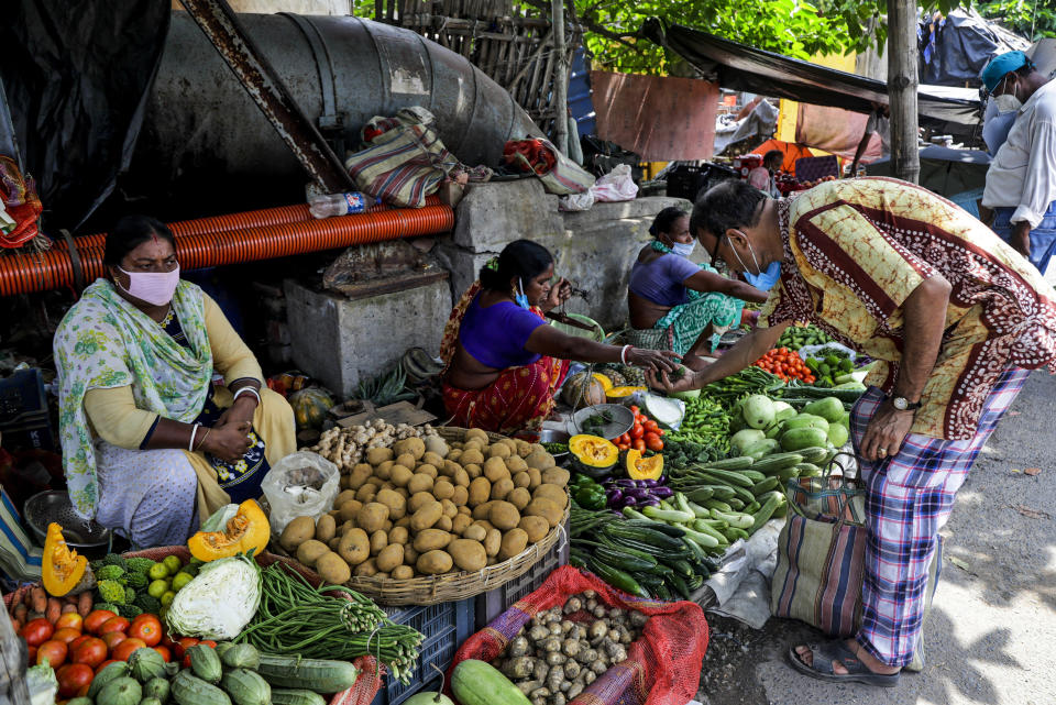 Vendors wearing face masks as a precaution against the coronavirus sell vegetables at roadside stalls in Kolkata, India, Sunday, Aug. 2, 2020. India is the third hardest-hit country by the COVID-19 pandemic in the world after the United States and Brazil. (AP Photo/Bikas Das)