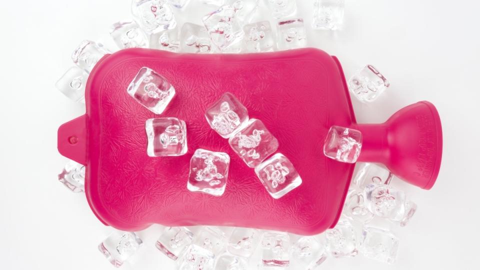 A pink hot water bottle with ice cubes on top of it