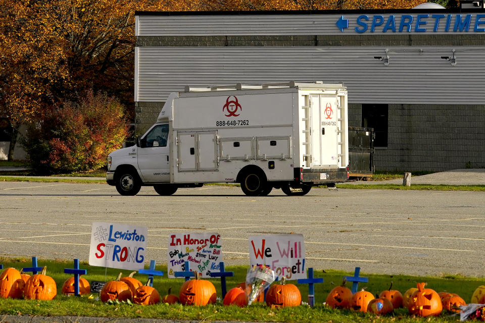 A memorial sit in front of Sparetime bowling as a hazmat crew arrives, Sunday, Oct. 29, 2023, in Lewiston, Maine. The community is working to heal following shooting deaths of 18 people at the bowling alley and a bar in Lewiston on Wednesday. (AP Photo/Matt York)