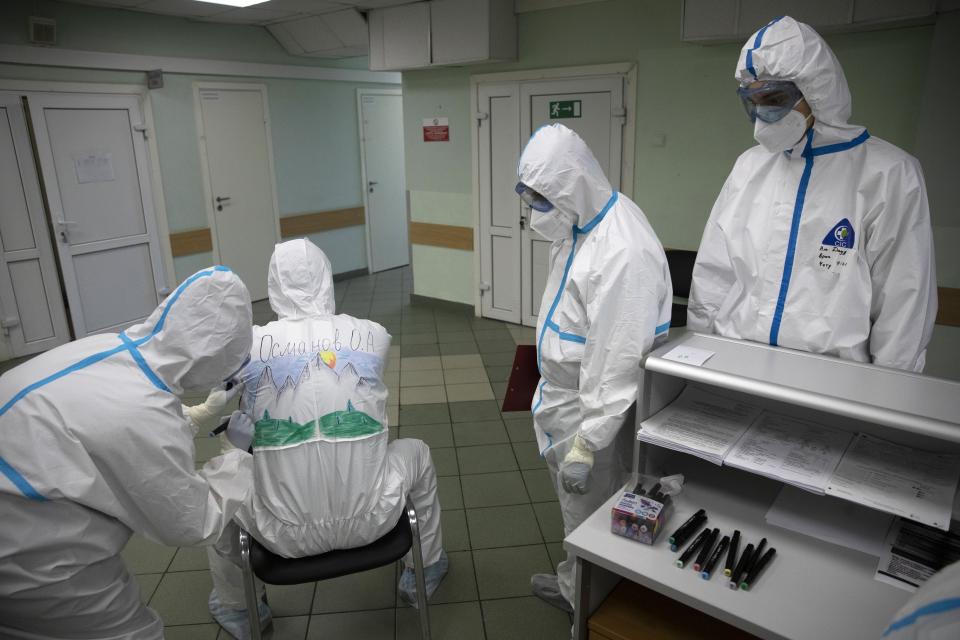 In this photo taken on Saturday, May 16, 2020, Dr. Osman Osmanov waits as a medical worker paints his protective gear during a rest on his shift at the Filatov City Clinical Hospital in Moscow, Russia. Moscow accounts for about half of all of Russia's coronavirus cases, a deluge that strains the city's hospitals and has forced Osmanov to to work every day for the past two months, sometimes for 24 hours in a row. (AP Photo/Pavel Golovkin)