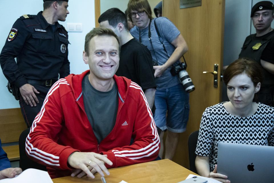 Russian leader Alexei Navalny, center, smiles as he speaks to the media prior to a court session in Moscow, Russia, Thursday, Aug. 22, 2019. Navalny is due in court, where a judge will consider extending his detention in lieu of days spent in hospital, where he was being treated for an allergic attack at the end of July. Navalny was due to be released on Friday after serving 30 days for calling an unsanctioned protest. (AP Photo/Alexander Zemlianichenko)