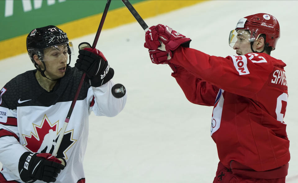 Artyom Shvets-Rogovoi of Russia, right, fight for a puck with Michael Bunting of Canada during the Ice Hockey World Championship quarterfinal match between Russia and Canada at the Olympic Sports Center in Riga, Latvia, Thursday, June 3, 2021. (AP Photo/Roman Koksarov)