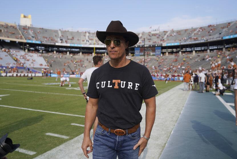 Actor Matthew Mcconaughey walks a football field wearing a cowboy hat and a t-shirt that says culture