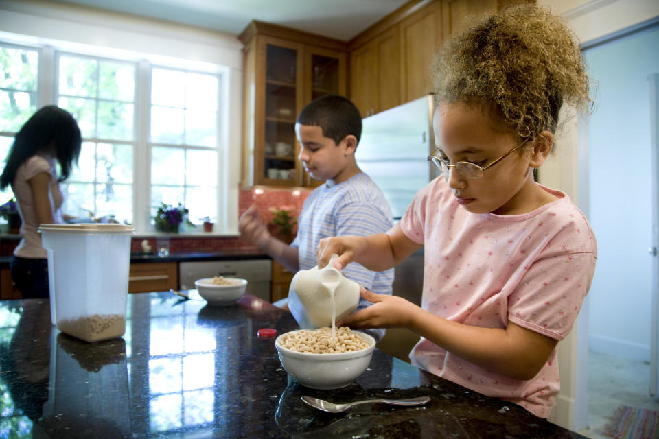A boy and a girl eating cereal at a kitchen island