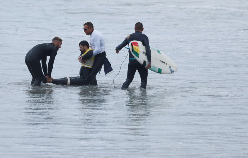 Surfer David Fernandez, who suffered an accident and left him having to use a wheelchair a year ago, is helped by his team after finishing his adaptive surfing competition in Las Palmas de Gran Canaria